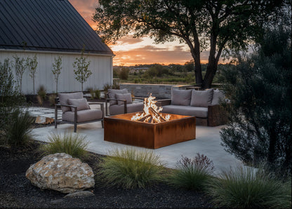 scenery shot of the square fire pit called the Jackson outside on the back patio of a house surround by outdoor furniture